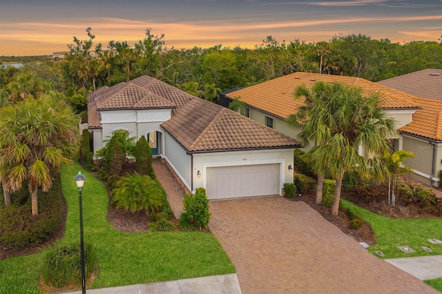 mediterranean / spanish-style house featuring a garage and a lawn