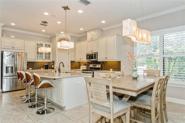 kitchen with decorative light fixtures, sink, stainless steel appliances, light tile patterned floors, and light stone counters