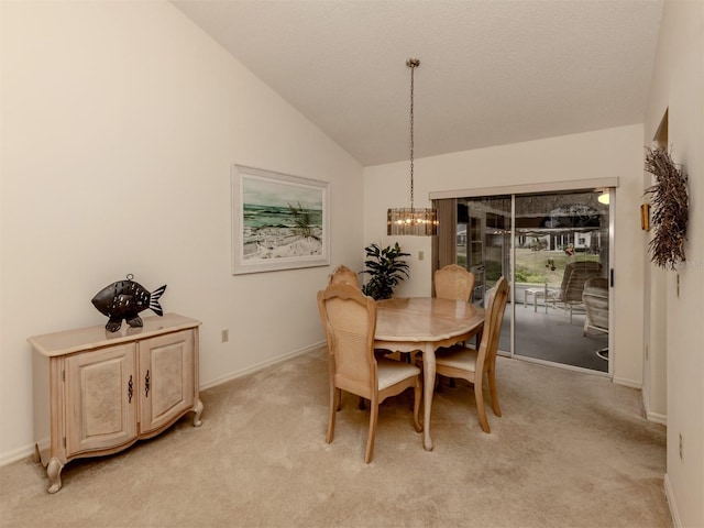 carpeted dining room featuring an inviting chandelier and high vaulted ceiling