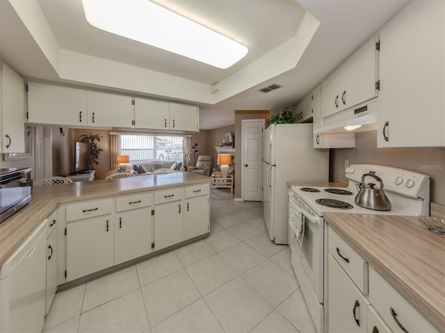 kitchen featuring white appliances, white cabinets, kitchen peninsula, a raised ceiling, and light tile patterned floors