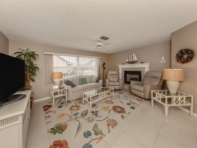 living room featuring a textured ceiling, ceiling fan, light tile patterned floors, and a fireplace