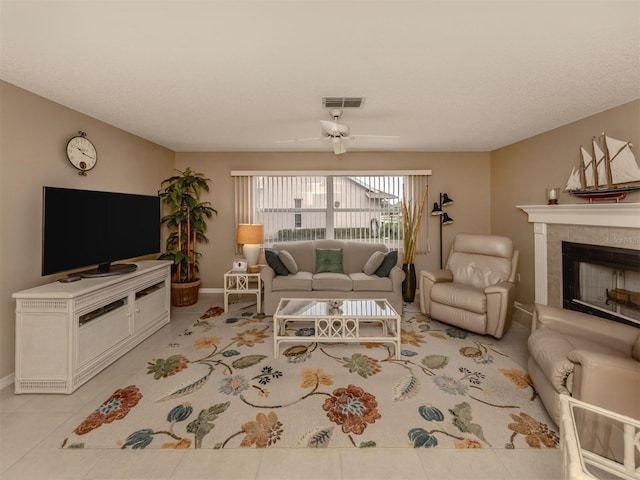 tiled living room featuring ceiling fan and a tiled fireplace