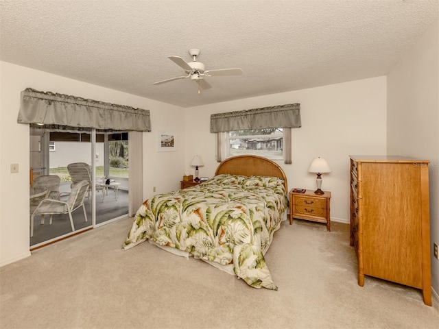 carpeted bedroom featuring ceiling fan, access to exterior, and a textured ceiling