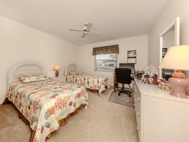 carpeted bedroom featuring ceiling fan and a textured ceiling