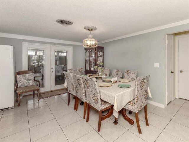 tiled dining space with a textured ceiling, french doors, and crown molding