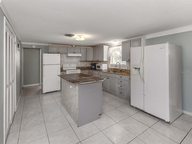 kitchen featuring white appliances, a textured ceiling, a kitchen island, and sink