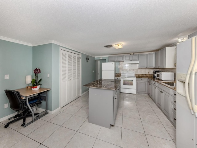 kitchen featuring white appliances, a textured ceiling, gray cabinets, and a center island