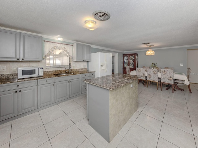 kitchen featuring sink, a center island, a textured ceiling, white appliances, and gray cabinets