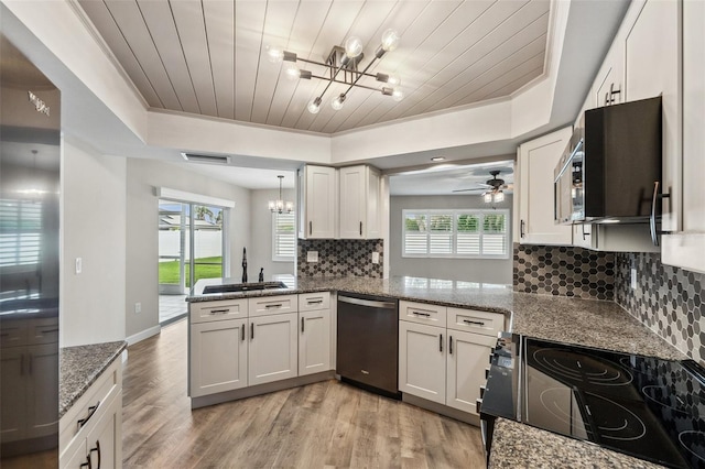 kitchen featuring a tray ceiling, kitchen peninsula, white cabinetry, and stainless steel dishwasher