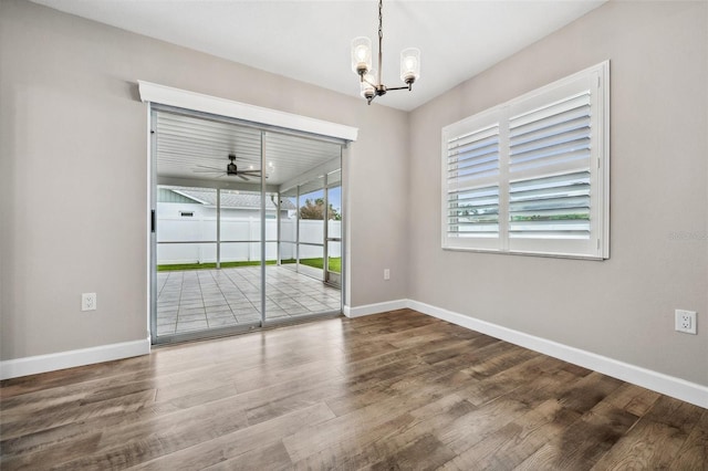 spare room featuring ceiling fan with notable chandelier and hardwood / wood-style flooring