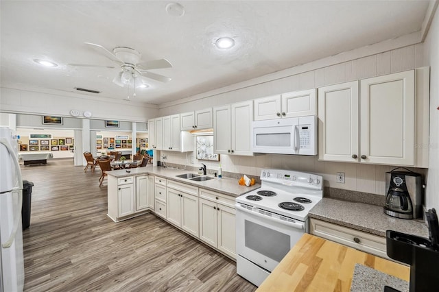 kitchen featuring white appliances, sink, kitchen peninsula, ceiling fan, and white cabinetry