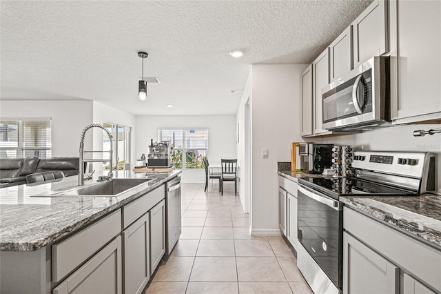 16766 Carlton Pond St, Wimauma, FL 33598 - kitchen with a textured ceiling, appliances with stainless steel finishes, sink, light tile patterned floors, and gray cabinetry