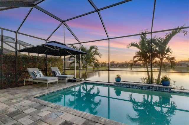 pool at dusk featuring a water view, a patio area, and glass enclosure