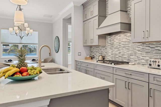 kitchen featuring gray cabinetry, sink, light stone counters, and custom range hood