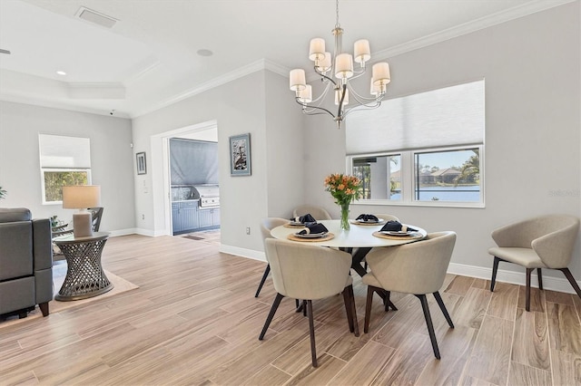 dining room with a notable chandelier, crown molding, and a raised ceiling