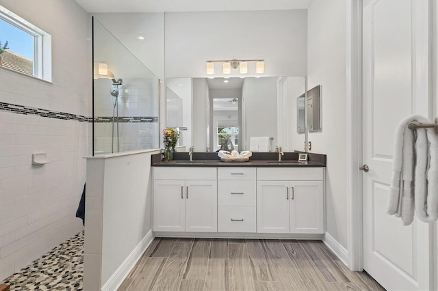 bathroom with a healthy amount of sunlight, vanity, and a tile shower