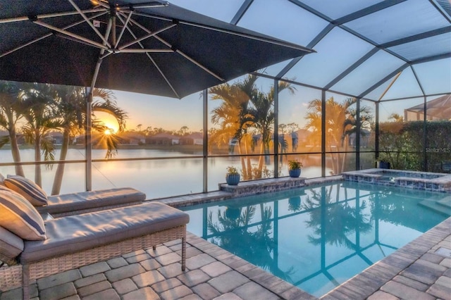 pool at dusk with a water view, a patio area, and a lanai