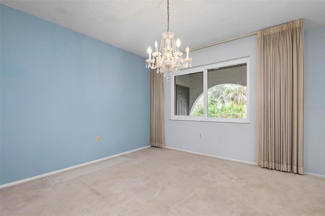 empty room featuring light colored carpet, a textured ceiling, and an inviting chandelier