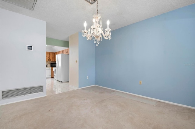 carpeted spare room featuring a textured ceiling and an inviting chandelier