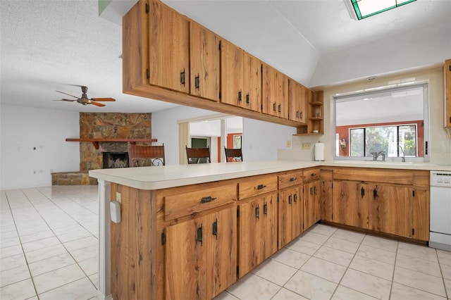 kitchen with kitchen peninsula, white dishwasher, a textured ceiling, a fireplace, and light tile patterned floors