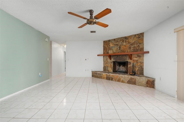 unfurnished living room with ceiling fan, a fireplace, light tile patterned floors, and a textured ceiling