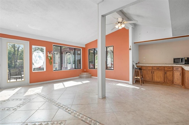 interior space featuring light tile patterned floors, vaulted ceiling with beams, and ceiling fan