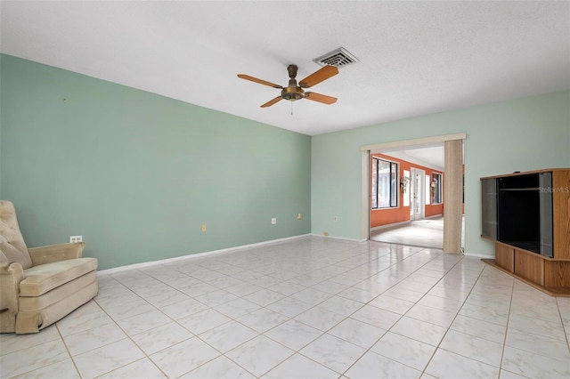 unfurnished living room featuring ceiling fan, light tile patterned floors, and a textured ceiling