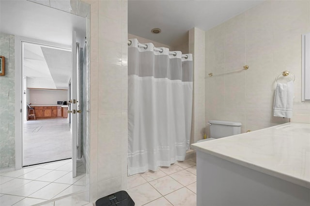 bathroom featuring a shower with shower curtain, vanity, tile walls, tile patterned flooring, and toilet