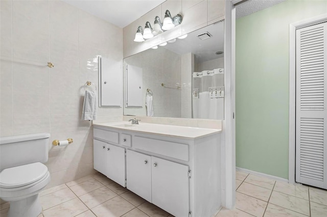 bathroom with a textured ceiling, vanity, tile walls, tile patterned flooring, and toilet