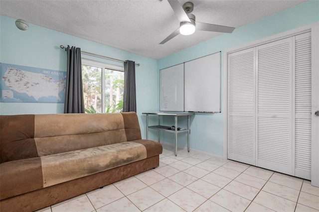 living room with ceiling fan, light tile patterned floors, and a textured ceiling