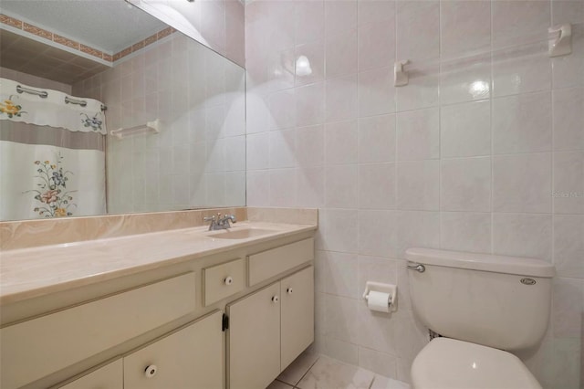 bathroom featuring tile patterned floors, vanity, toilet, and tile walls