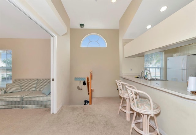 kitchen with white fridge, light colored carpet, and sink