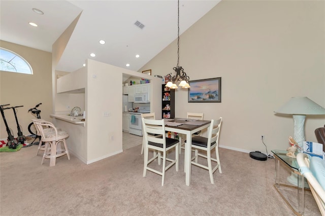 carpeted dining space featuring sink, high vaulted ceiling, and an inviting chandelier