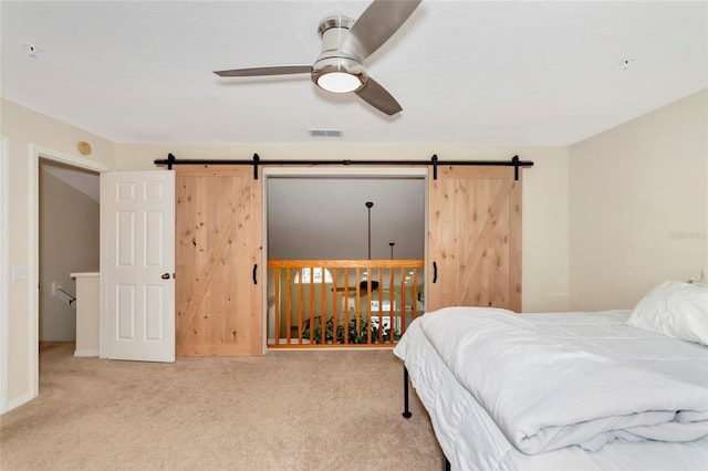 carpeted bedroom featuring a barn door and ceiling fan