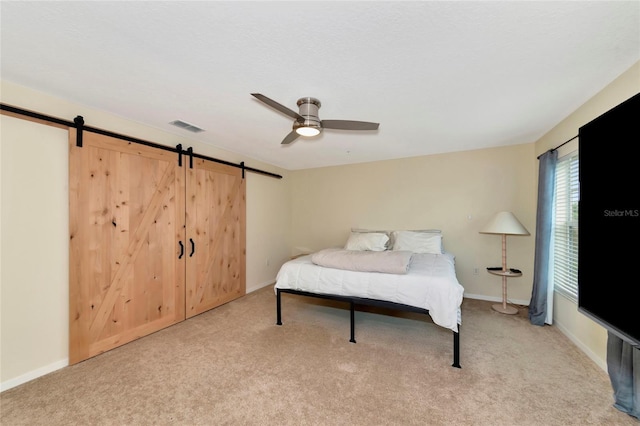 bedroom with a barn door, light colored carpet, and ceiling fan