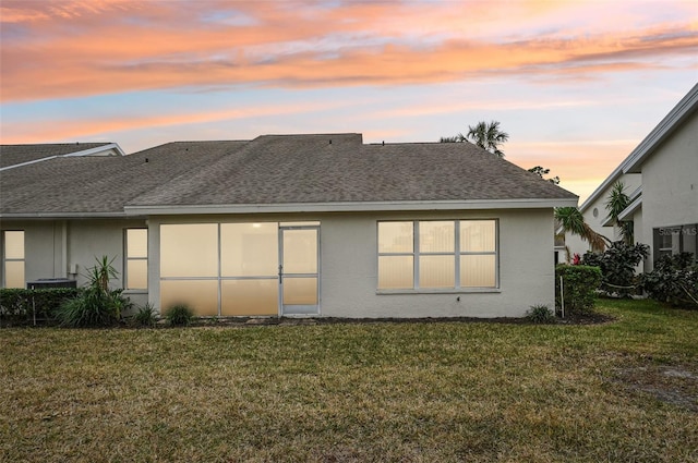 back house at dusk with a lawn