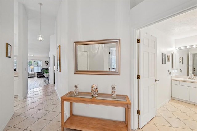 hall with sink, light tile patterned floors, and a chandelier