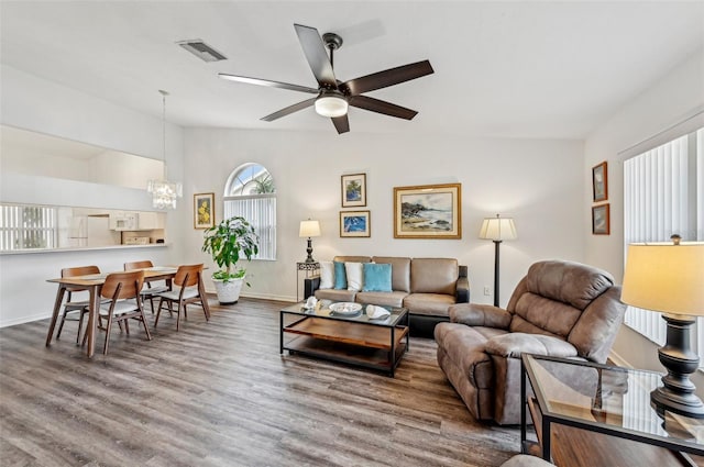 living room with ceiling fan with notable chandelier and hardwood / wood-style flooring