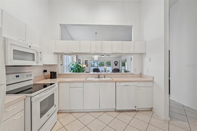 kitchen with light tile patterned floors, sink, white appliances, and white cabinetry