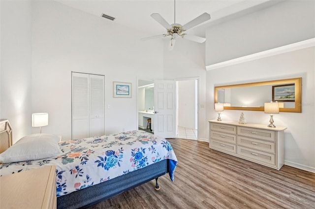 bedroom with a closet, light hardwood / wood-style flooring, a high ceiling, and ceiling fan