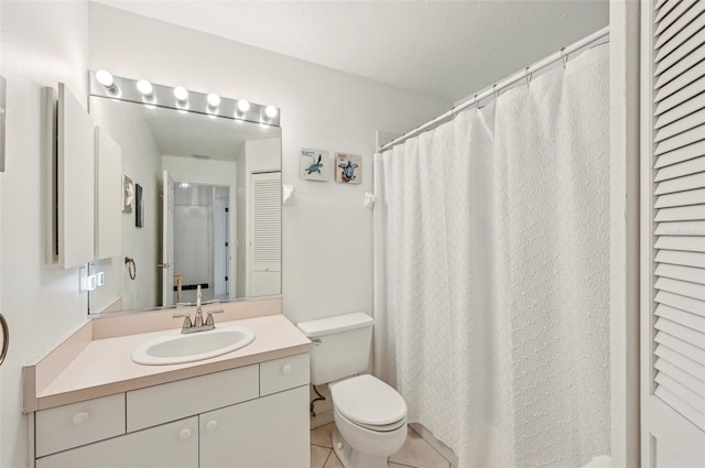 bathroom with toilet, vanity, and tile patterned floors