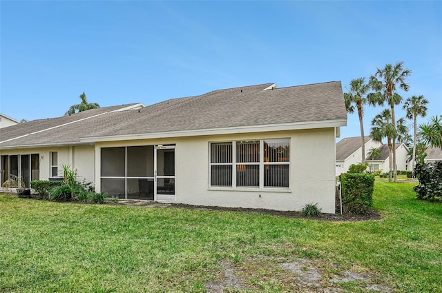 rear view of house featuring a yard and a sunroom