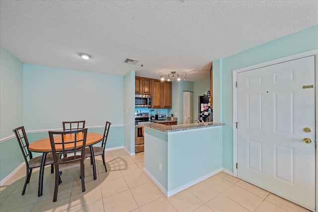 kitchen with light tile patterned floors, a textured ceiling, appliances with stainless steel finishes, and kitchen peninsula