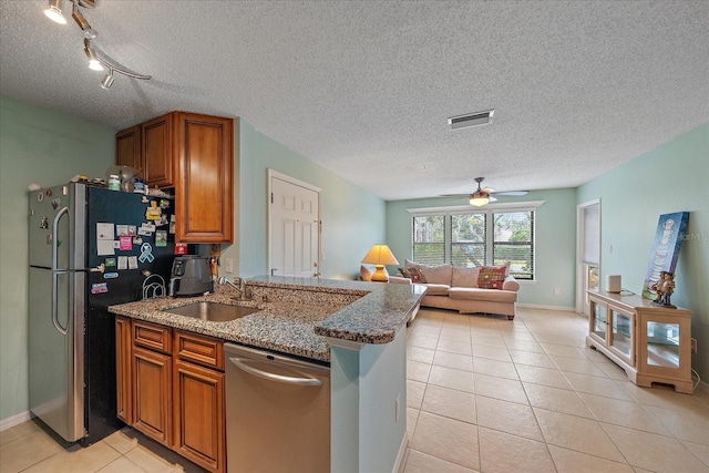 kitchen with ceiling fan, appliances with stainless steel finishes, stone countertops, and sink