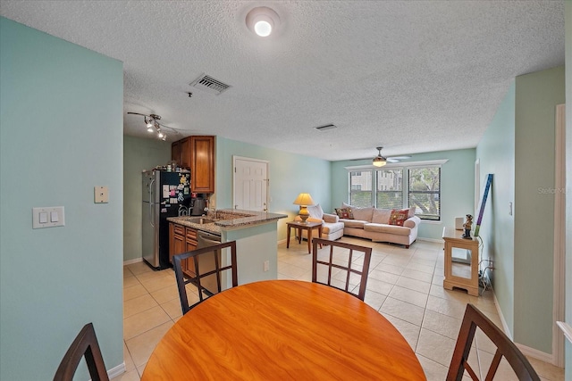 tiled dining room with ceiling fan and a textured ceiling