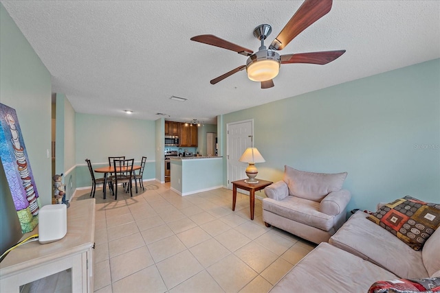 living room with a textured ceiling, ceiling fan, and light tile patterned floors