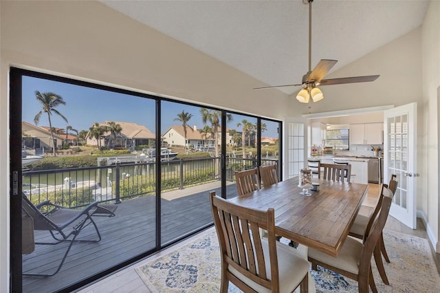 dining area featuring lofted ceiling, french doors, a water view, ceiling fan, and light wood-type flooring