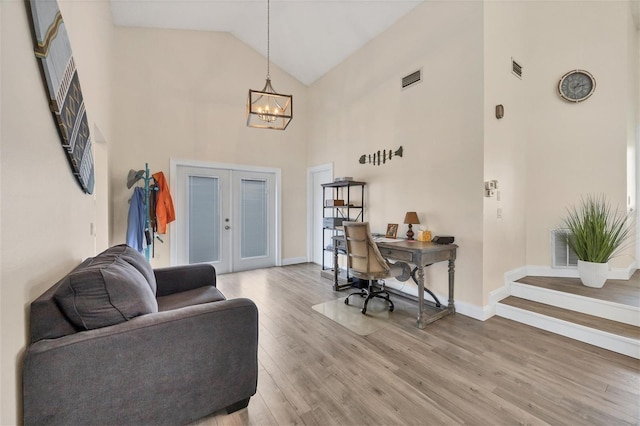 office area with hardwood / wood-style floors, high vaulted ceiling, french doors, and a notable chandelier