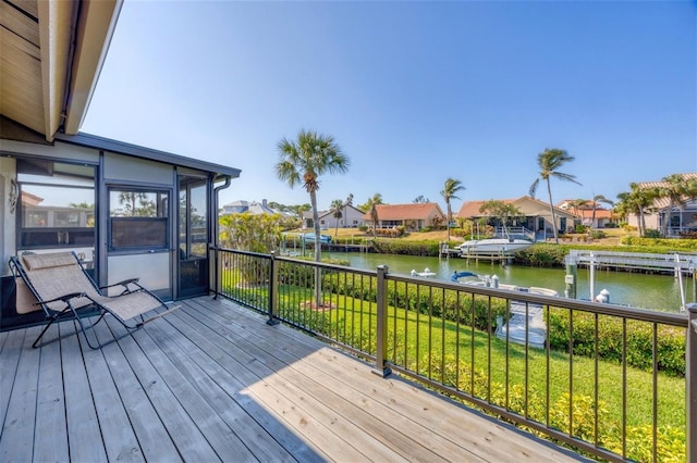 deck with a sunroom, a water view, and a yard