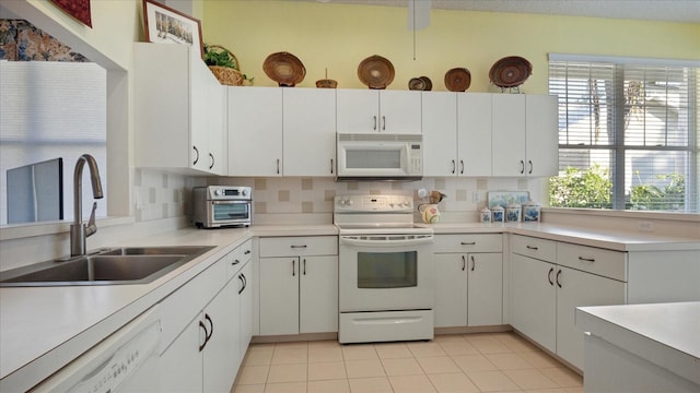 kitchen featuring decorative backsplash, white cabinetry, sink, and white appliances